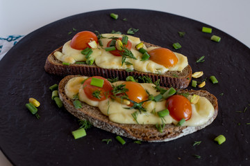 Multigrain toast bread with melt gouda or kaseri cheese and small tomatoes and green onion on top 