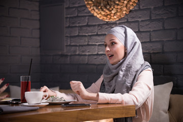 Fototapeta na wymiar Young muslim woman sitting in cafe with her friend