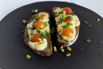 Multigrain toast bread with melt gouda or kaseri cheese and small tomatoes and green onion on top 