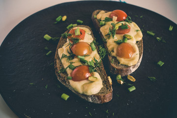 Multigrain toast bread with melt gouda or kaseri cheese and small tomatoes and green onion on top 