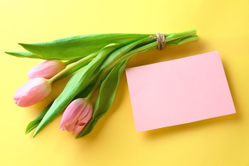 Bouquet of beautiful tulips and blank card on color background