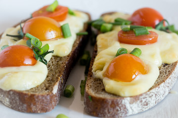 Multigrain toast bread with melt gouda or kaseri cheese and small tomatoes and green onion on top 