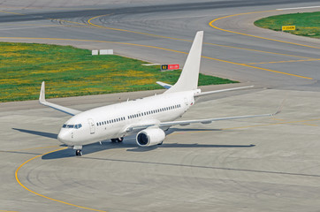 View of the steering track and runway with a white passenger airplane on the airport apron