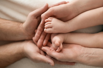 Obraz na płótnie Canvas Parents holding feet of cute little baby at home