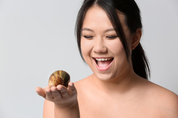 Asian woman with giant Achatina snail on light background