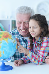 Fototapeta premium Portrait of grandfather and granddaughter exploring world globe
