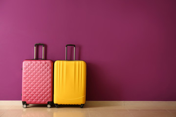 Packed suitcases near color wall