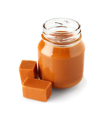Jar with sweet liquid caramel on white background