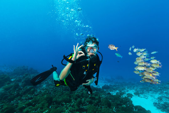Young woman scuba diver showing OK gesture.