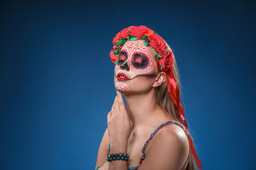 Fototapeta premium Young woman with painted skull on her face for Mexico's Day of the Dead against color background