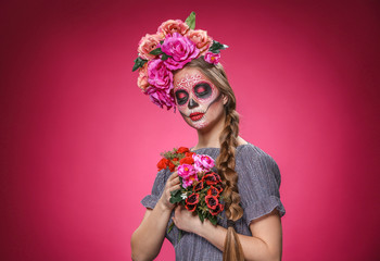 Young woman with painted skull on her face for Mexico's Day of the Dead against color background