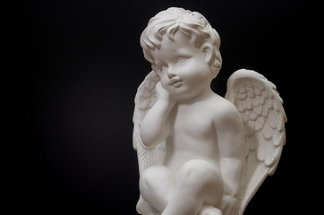 Beautiful white angel on black background close-up. Symbol of love, faith and hope