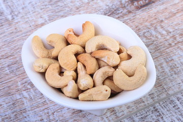nuts cashews in white bowl on wooden background. Selective focus.