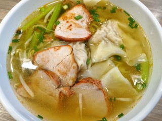 Top view of shrimp wonton with bbq pork and clear soup topped with sliced scallion in white bowl, Kiao Nam is Thai traditional