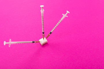 white medical syringes stick out of a piece of sugar