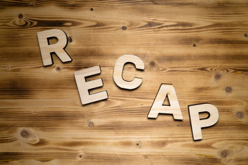 RECAP word made of wooden block letters on wooden board, top view.