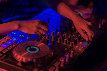 Close up, DJ mixing tracks on a mixer in a nightclub.
