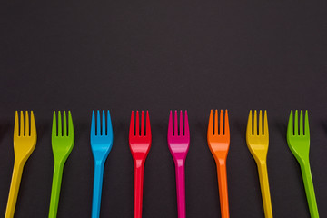 Many color plastic forks on a bright background