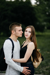 portrait of two students carrying bags walking and talking in a park