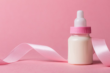Baby bottle on a pastel pink background. New baby arrival