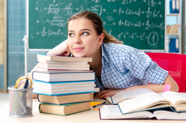 Female student with many books sitting in the classroom