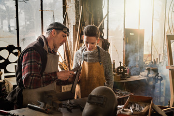 A craftsman in his workshop teaches his work to his apprentice