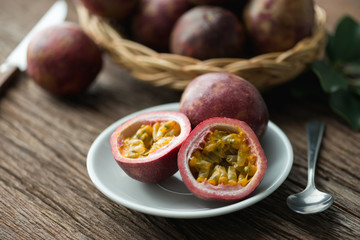 Half of  passion fruit on plate and organic passionfruit on wood basket, wooden background.