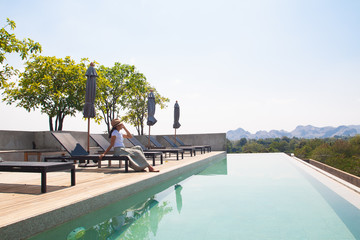 Asian woman relaxing at swimming pool on the roof top