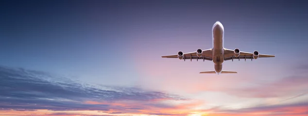 Foto op Plexiglas Commercieel vliegtuigstraalvliegtuig dat boven dramatische wolken in prachtig zonsonderganglicht vliegt. Reisconcept. © Lukas Gojda