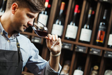 Bokal of red wine on background, male sommelier appreciating drink