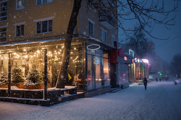  winter evening in the city. snowy street. cafe with yellow lights
