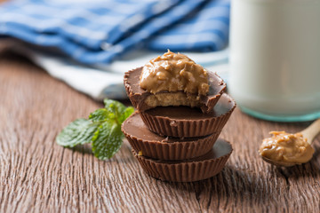 Homemade peanut butter cup, stack of dark chocolate with milk bottle, dessert food.