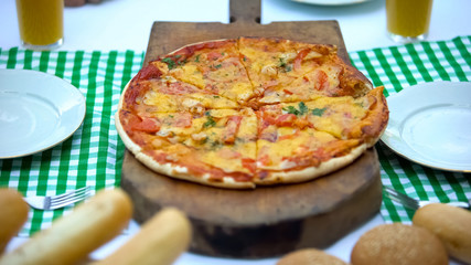 Delicious pizza lying on huge wooden board in fast food restaurant, culinary