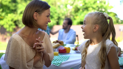 Happy mother and daughter sharing secrets on backyard of cottage, girls talks