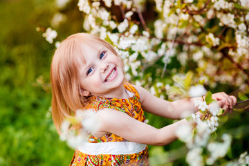 Fototapeta premium cute little girl near blooming apple trees and cherry