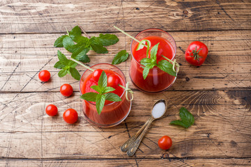 Tomato juice with mint in glass and fresh tomatoes on a wooden table. Healthy organic food concept