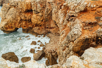 landscape of orange rocks and ocean waves Portugal, Sagres