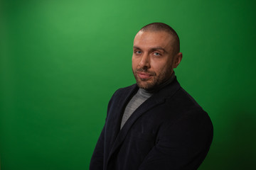 Fototapeta premium Studio fashion portrait in monochrome. Elegant young handsome serious man iin studio with green background.