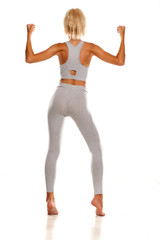 Back view of slim sporty young woman in gray leggings on white background