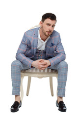 A man in a suit is sitting on an expensive chair.