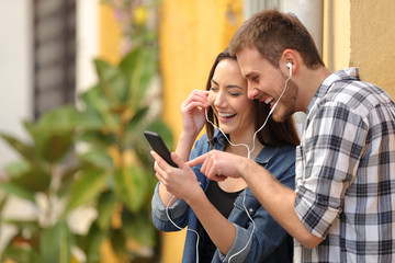 Happy couple laughing listening to music online