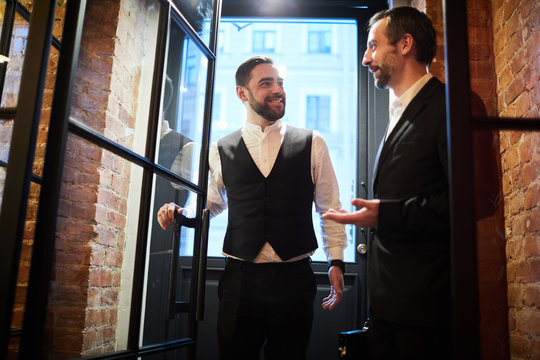 Front view portrait of two handsome gentlemen entering cafe chatting cheerfully, copy space