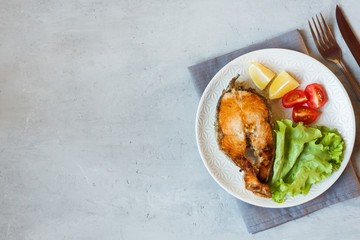 Steak baked salmon fish on a plate with fresh vegetables.