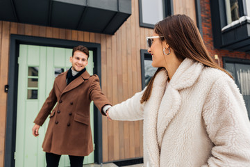 Stylish wife wearing warm beige coat asking her man to go for a walk