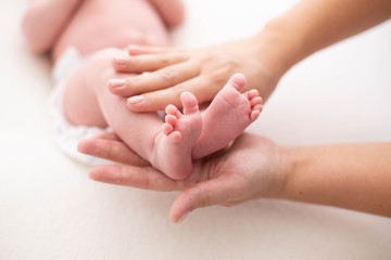 Fototapeta na wymiar Baby feet cupped into mothers hands. Gentle blurred background of the feet and heels of a newborn