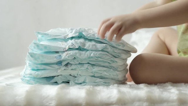 Child plays with baby diapers in a pile, baby, background, diaper