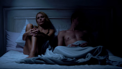 Fototapeta na wymiar Offended couple sitting on bed and ignoring each other, misunderstanding