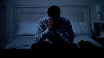 Disappointed businessman sitting on bed at home, startup failure, problems