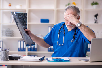 White bearded old doctor radiologist working in clinic 