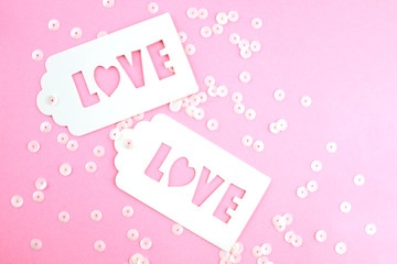 White gift tag with inscription love on a pink background.